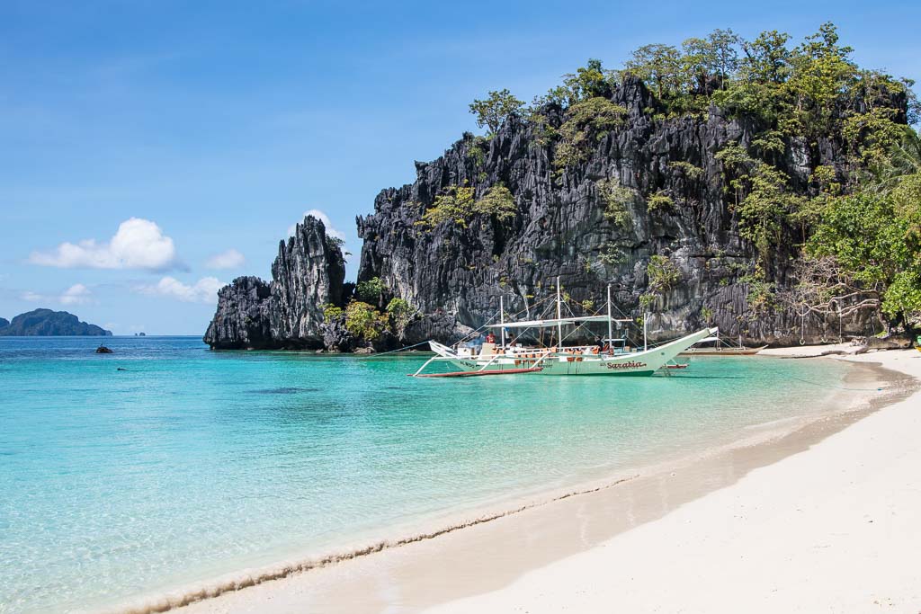 Picture of a sunny day on the El Nido beach with a ferry docked