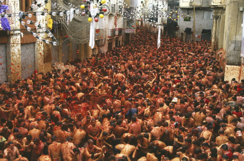 Picture of people covered in tomato paste during the tomato festival in Spain