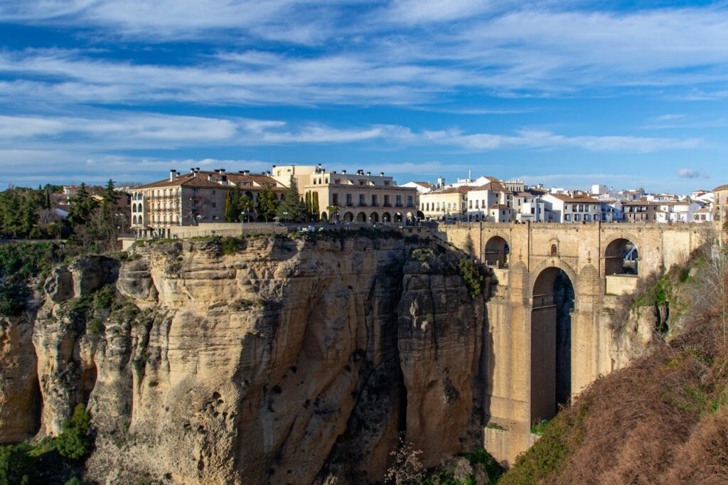 Picture of Ronda buildings close to a cliff on a sunny afternoon.